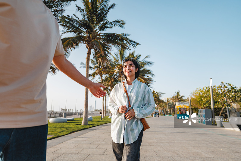 一对快乐的混血年轻情侣在吉达滨海大道散步图片素材