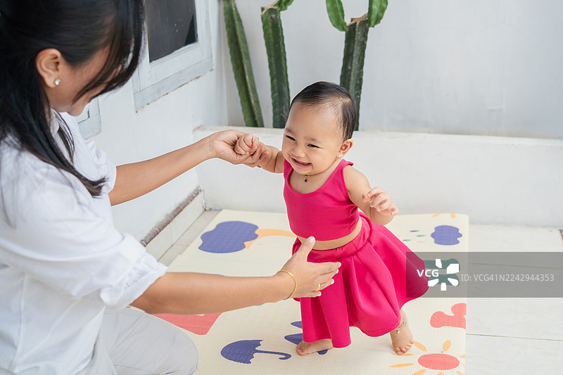 小女孩在妈妈的陪伴下学习走路，掌握平衡图片素材