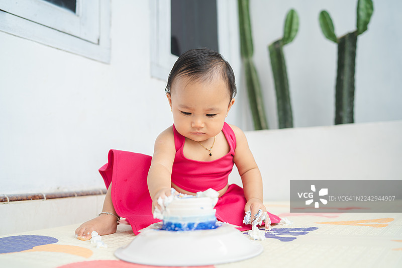 小女孩在地垫上玩生日蛋糕，玩得很开心图片素材