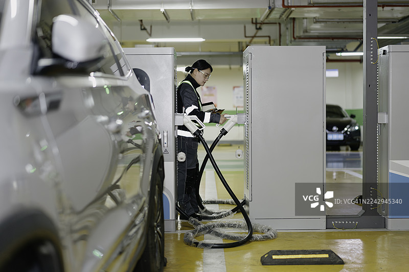 一名员工正在检查电动汽车充电站的设施。图片素材