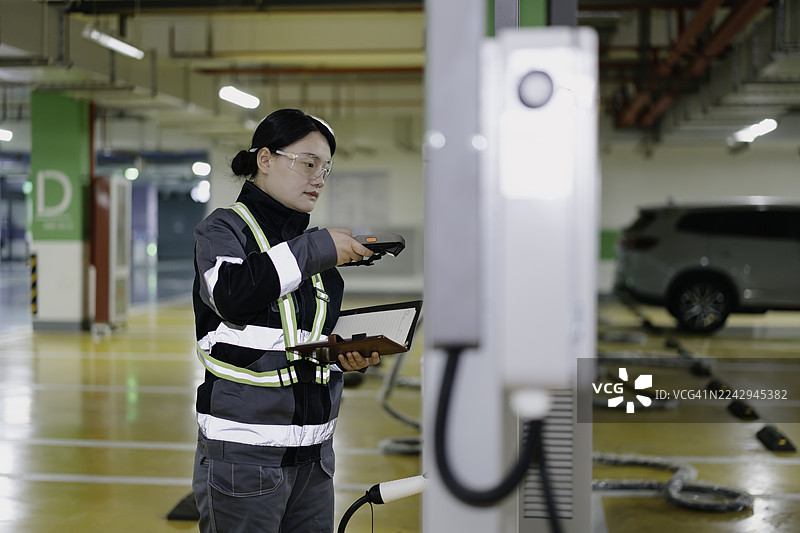 一位亚裔女性电气工程师正在检查电动汽车充电站。图片素材