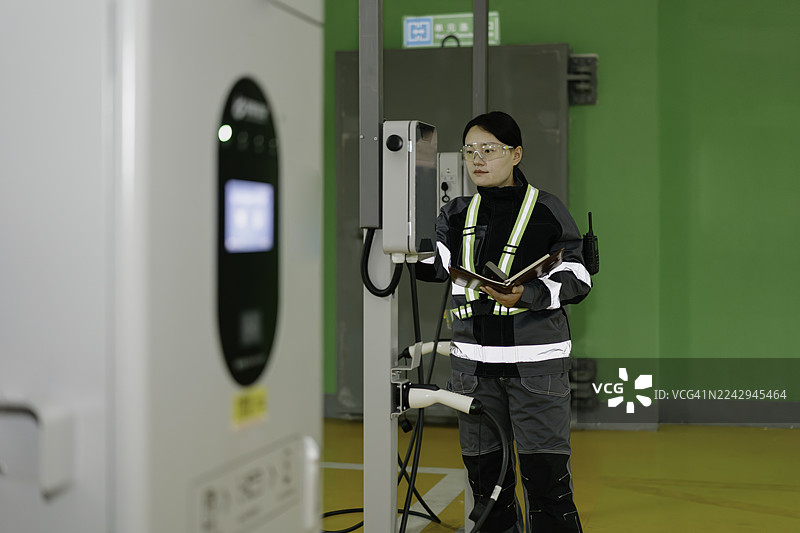 一名员工正在检查电动汽车充电站的设施。图片素材