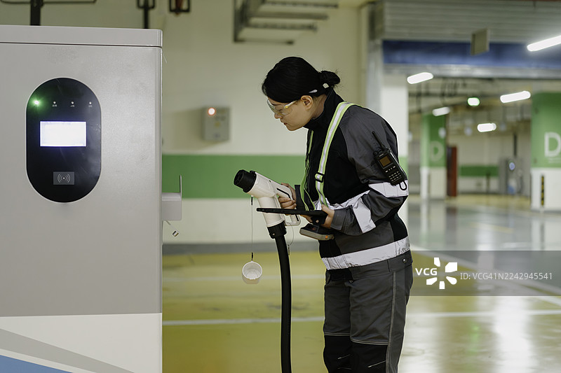一名员工正在检查电动汽车充电站的设施。图片素材