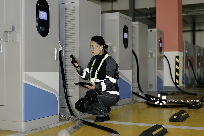 一位亚裔女性电气工程师正在检查电动汽车充电站。图片素材