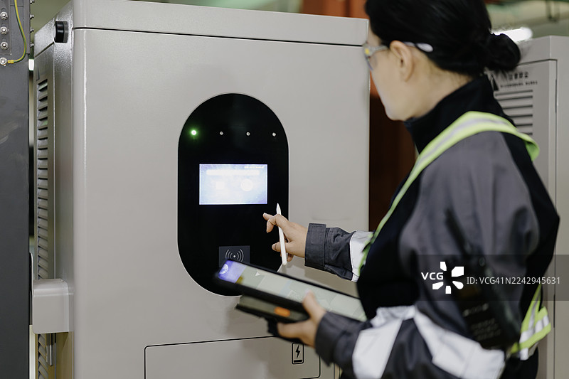一名员工正在检查电动汽车充电站的设施。图片素材