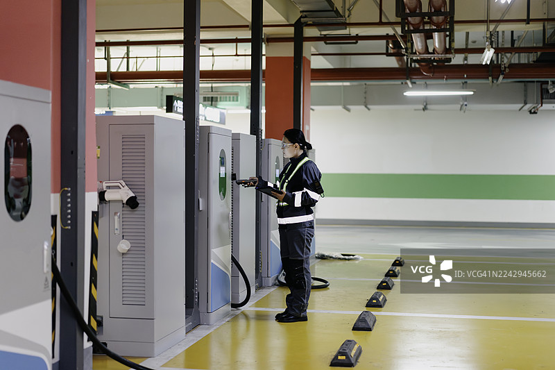 一位亚裔女性电气工程师正在检查电动汽车充电站。图片素材