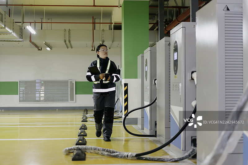 一名员工正在检查电动汽车充电站的设施。图片素材