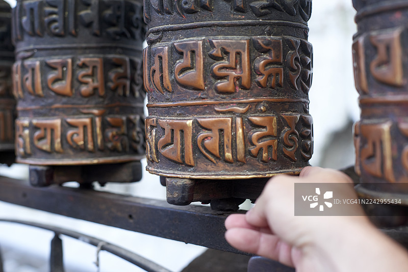 一个人在旋转刻有咒语的佛教转经轮图片素材