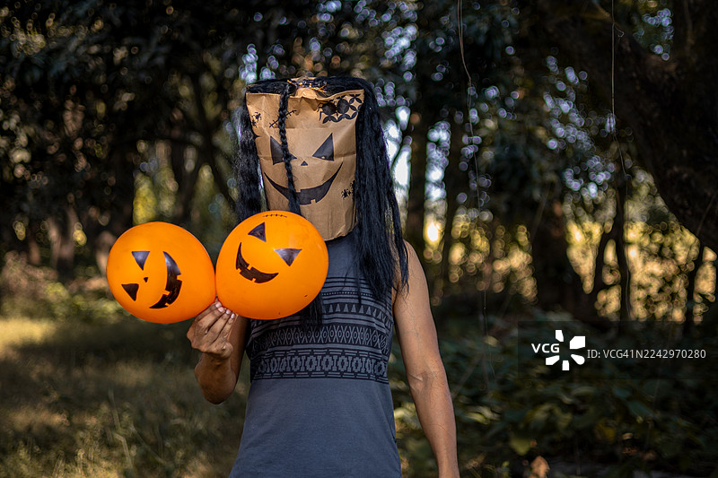 戴着万圣节面具、手持南瓜气球的神秘男子图片素材