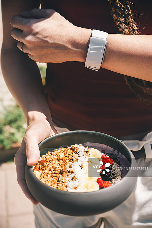 手工制作的格兰诺拉麦片，搭配酸奶和新鲜水果，手持。图片素材