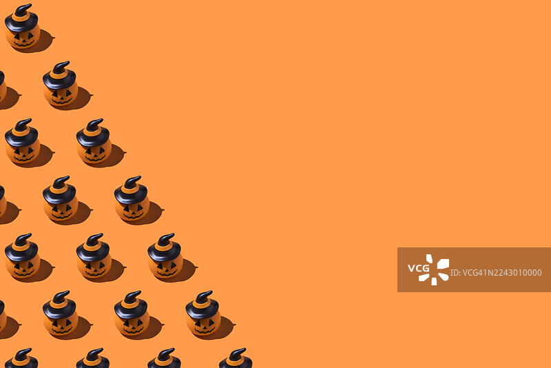 万圣节南瓜图案，位于左侧，橙色背景。万圣节庆典概念，亡灵节，逝者与圣徒，恐怖，恐惧图片素材
