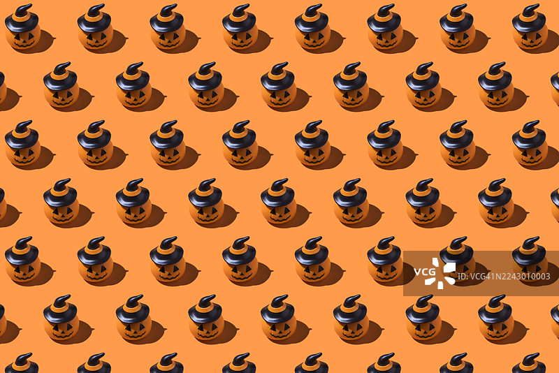 橙色背景上的万圣节南瓜图案。万圣节庆典概念，亡灵节，逝者与圣徒，恐怖，恐惧图片素材