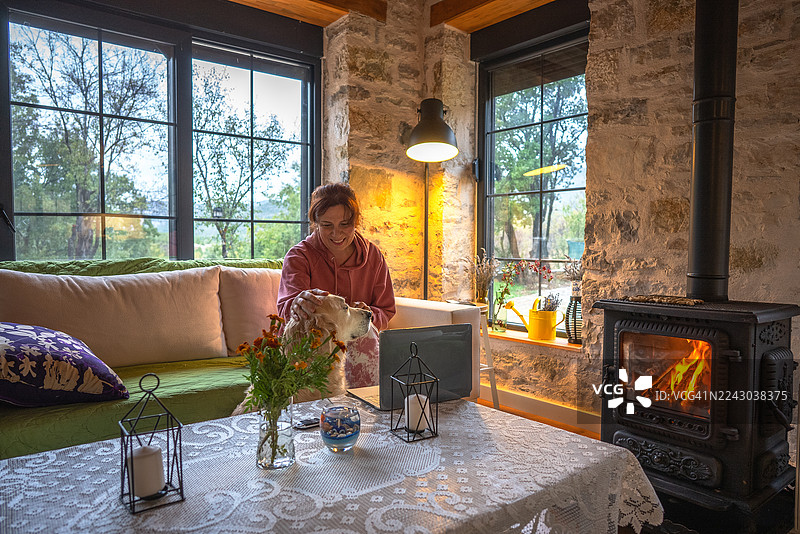 女人坐在窗边的沙发上，照顾着她的狗图片素材