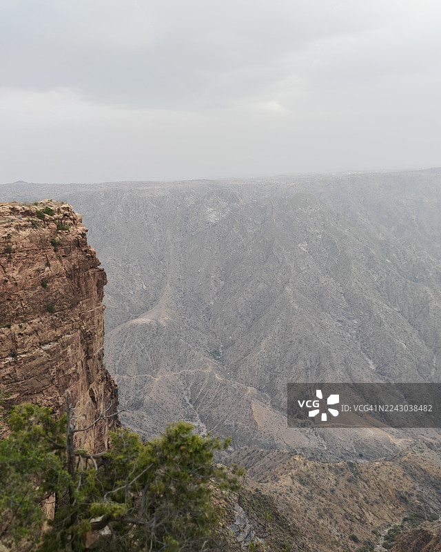 阴天之下，崎岖的岩石山脉和广阔的山谷构成了一幅戏剧性的壮丽景色，展现了大自然的宏伟图片素材