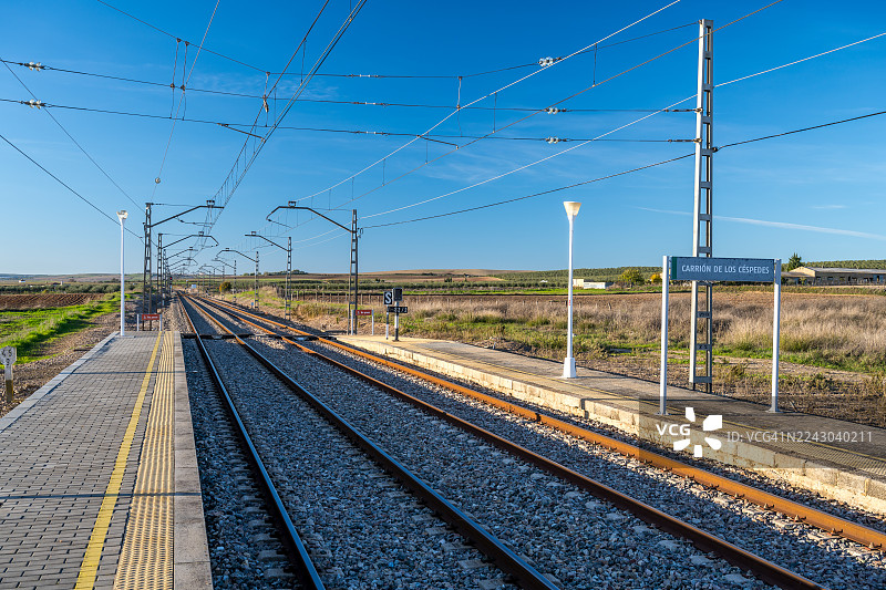 西班牙卡林德洛斯科尔佩斯乡村火车站，俯瞰铁轨和高架电线，背景是湛蓝的天空图片素材