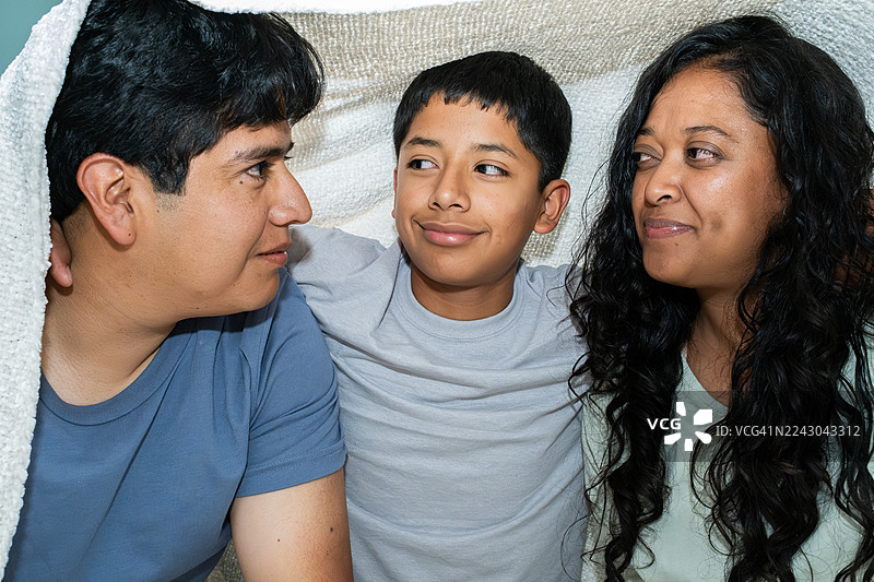 拉丁夫妇和他们十几岁的儿子在墨西哥城的一条毯子下玩耍图片素材
