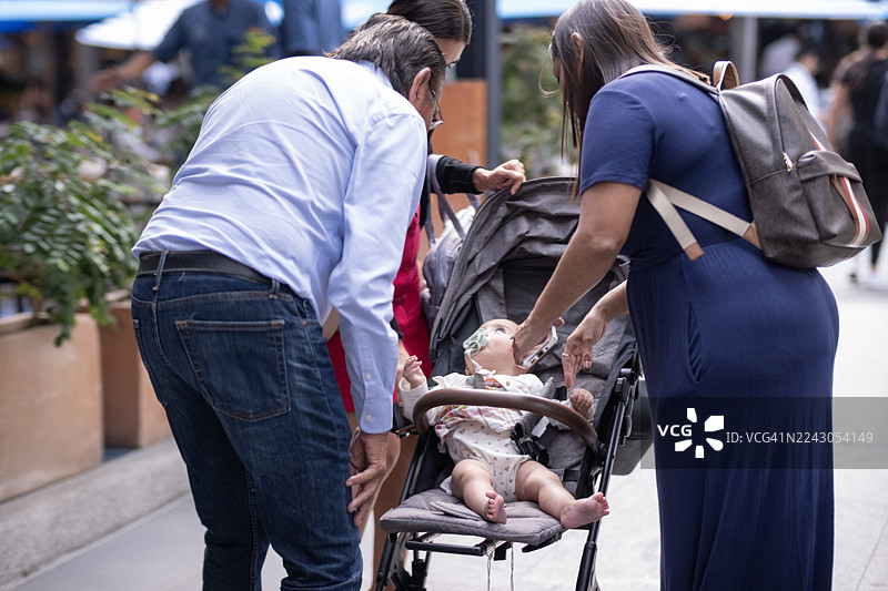 一家人推着婴儿车，漫步在城市的广场和购物中心。图片素材