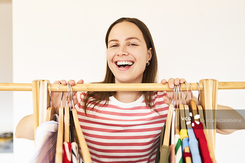快乐的年轻女子在衣架上挑选服装图片素材