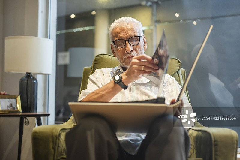 一位老人看着他的相册，回忆着生命中定格在照片里的美好旧时光。图片素材
