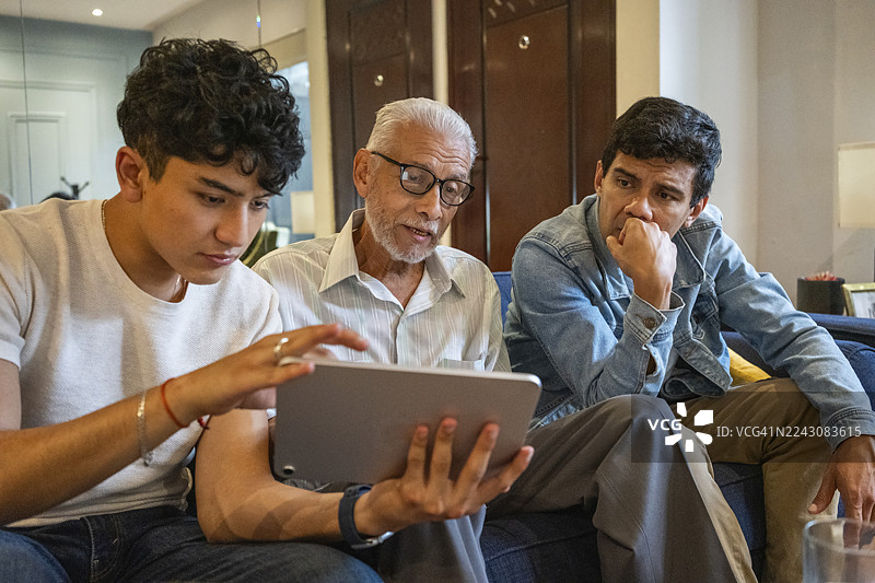 男人们和家人一起观看电视上的足球比赛，同时查阅足球统计数据、比赛数据和联赛排名。图片素材