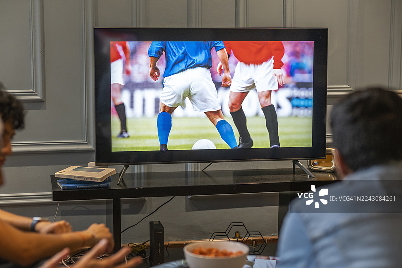 一家人一起享受足球比赛，共度美好时光，在家为他们最喜欢的球队加油助威图片素材