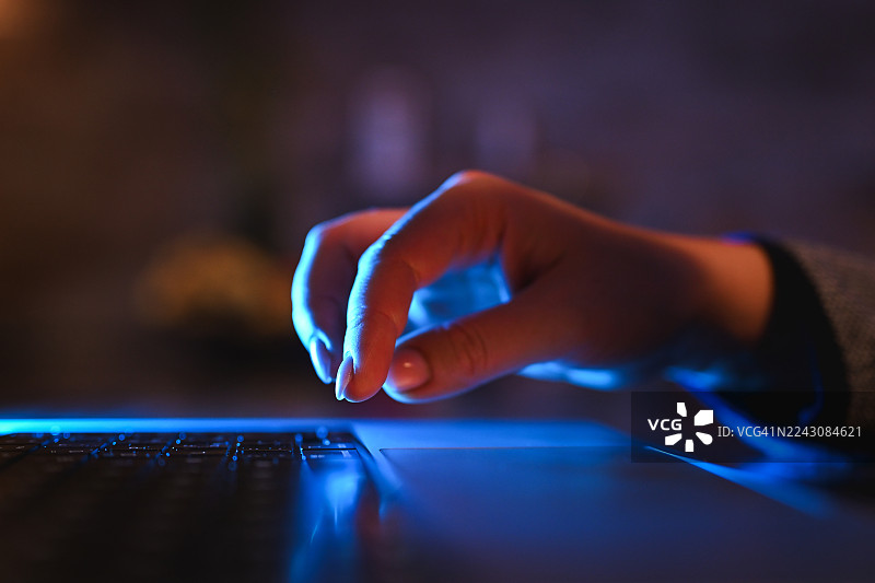 夜间特写：手在笔记本电脑键盘上打字图片素材