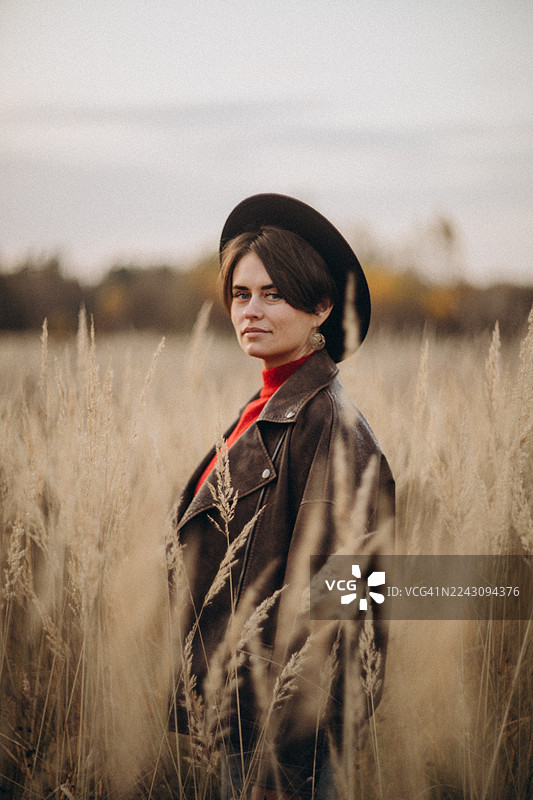 戴着帽子的女士在秋日高高的田野里摆姿势图片素材
