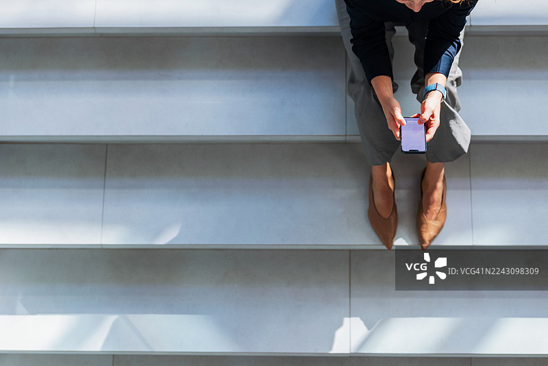女子在简约现代的楼梯上使用智能手机图片素材