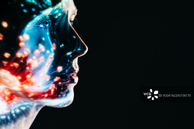 黑暗中，一位女性的剪影轮廓叠加着多彩的数字灯光投影。图片素材