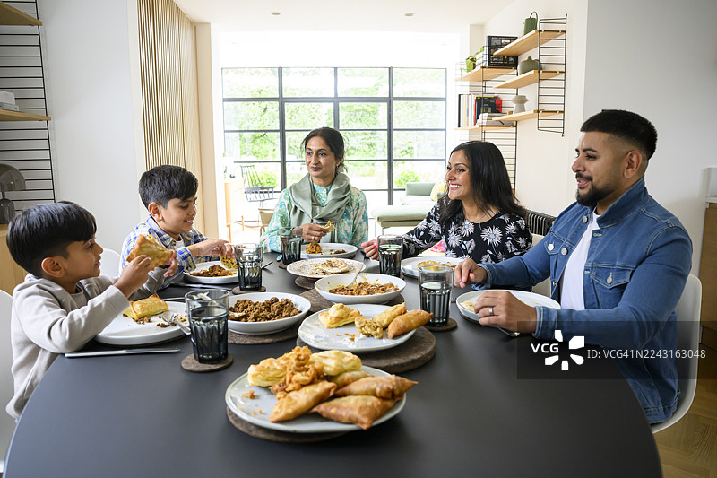 英裔巴基斯坦家庭在现代餐厅里享用传统家常菜图片素材
