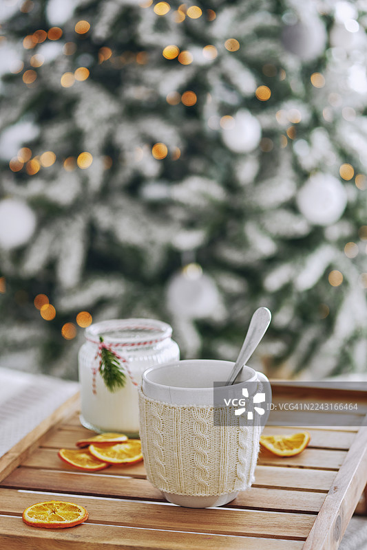 温暖的马克杯放在托盘上，靠近圣诞树，特写图片素材