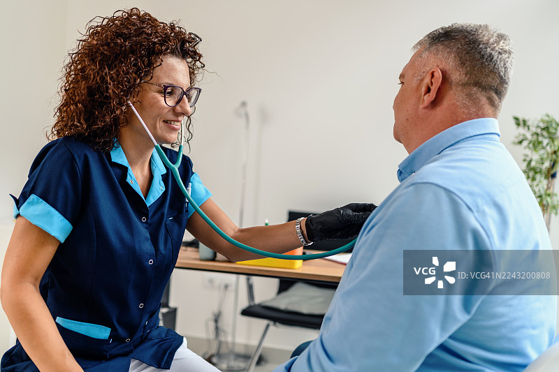 女医生在诊疗室里用听诊器听诊男病人的病情图片素材