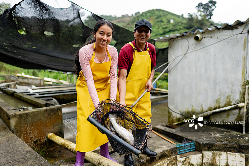 虹鳟鱼养殖场员工在混凝土育种池工作的肖像图片素材