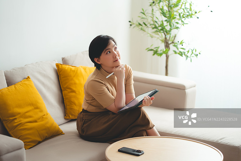 亚洲女性使用智能笔在数码平板电脑屏幕上书写图片素材