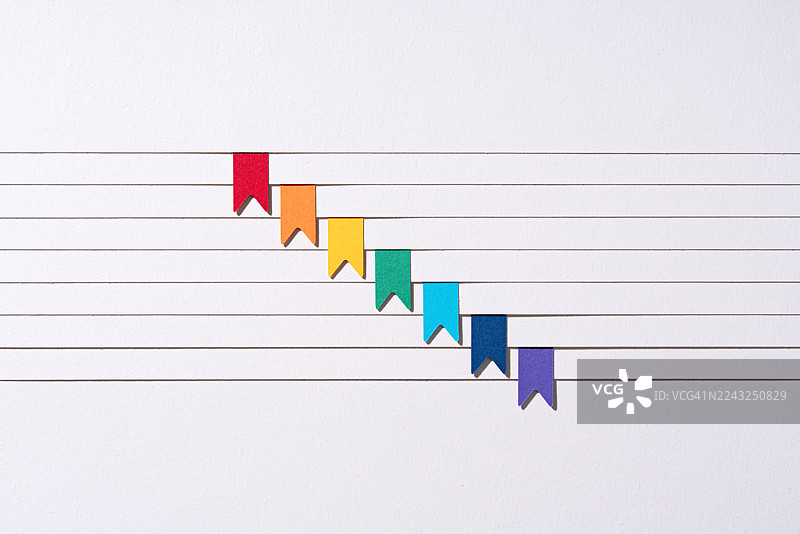 彩虹书签夹在分层的白纸边缘图片素材