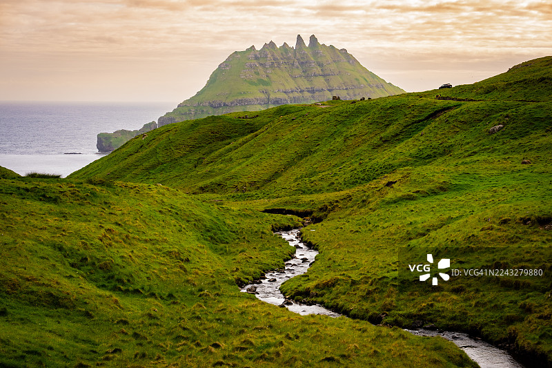 一条小溪流入大海，背景是廷多尔穆尔山。图片素材