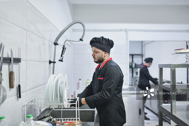 大厨在现代厨房洗碗，专业厨师在繁忙餐厅服务后清洁盘子图片素材