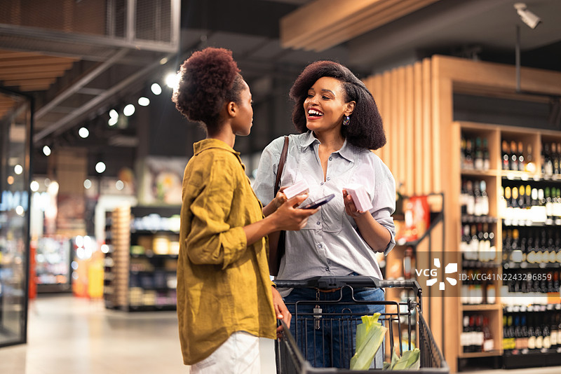 一位母亲和女儿在现代超市里享受购物和交谈的时光图片素材