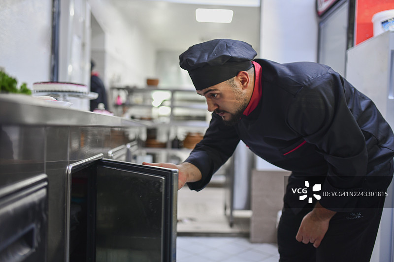 专业厨师在繁忙的商业厨房中检查厨房储存的新鲜食材图片素材