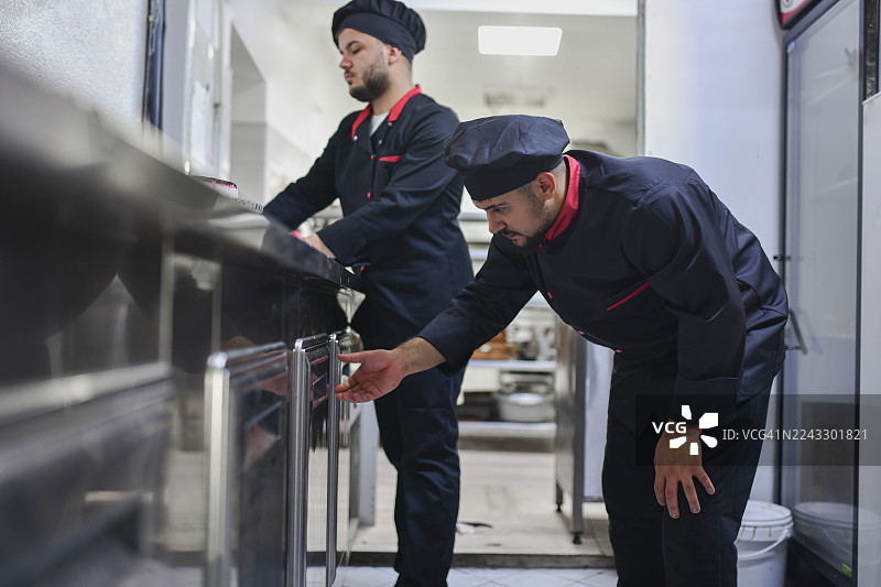 专业厨师在繁忙的商业厨房中检查厨房储藏室的新鲜食材图片素材