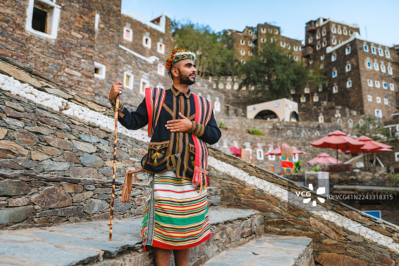 一位身着阿西里服饰的沙特男子在历史遗迹中，神情宁静图片素材