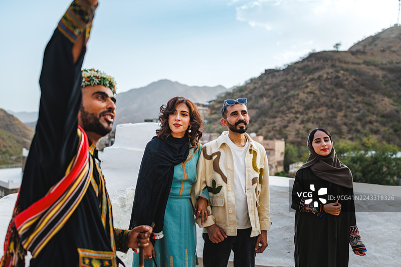 一群人兴致勃勃地聆听身着传统阿西里服饰的沙特导游在里贾尔·阿尔马介绍图片素材