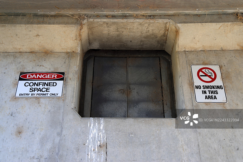 澳大利亚首都领地惠特兰莫洛洛河保护区巴特斯桥下的维护通道入口处，设有“危险：密闭空间。仅凭许可证进入”和“此区域禁止吸烟”的警示牌。图片素材