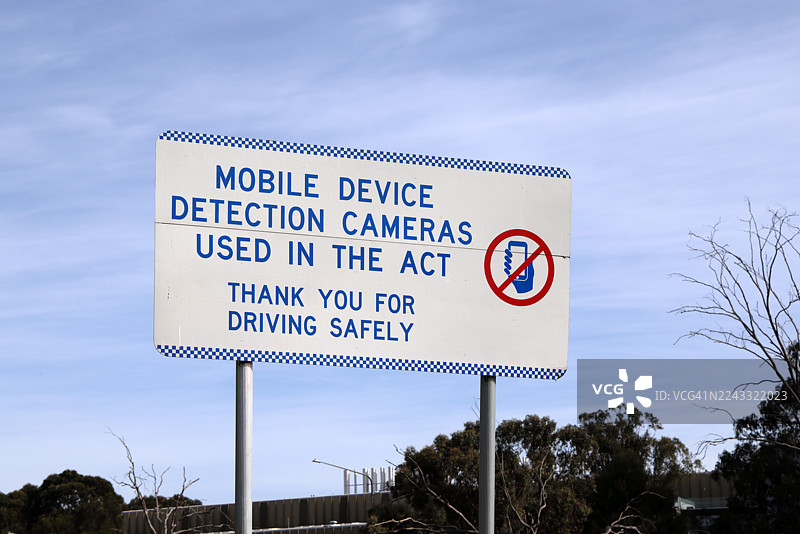 澳大利亚首都堪培拉的公园大道旁，设有‘首都行政区使用手机检测摄像头，感谢您安全驾驶’的交通警示牌。图片素材
