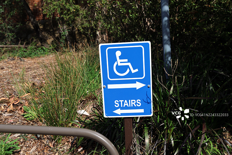 一个指示牌，指示一个方向是楼梯，另一个方向是无障碍通道。图片素材