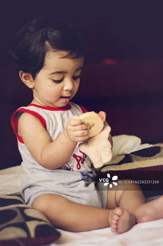 好奇的玩耍时光：可爱的小孩在家中玩玩具。印度小男孩的特写肖像。图片素材