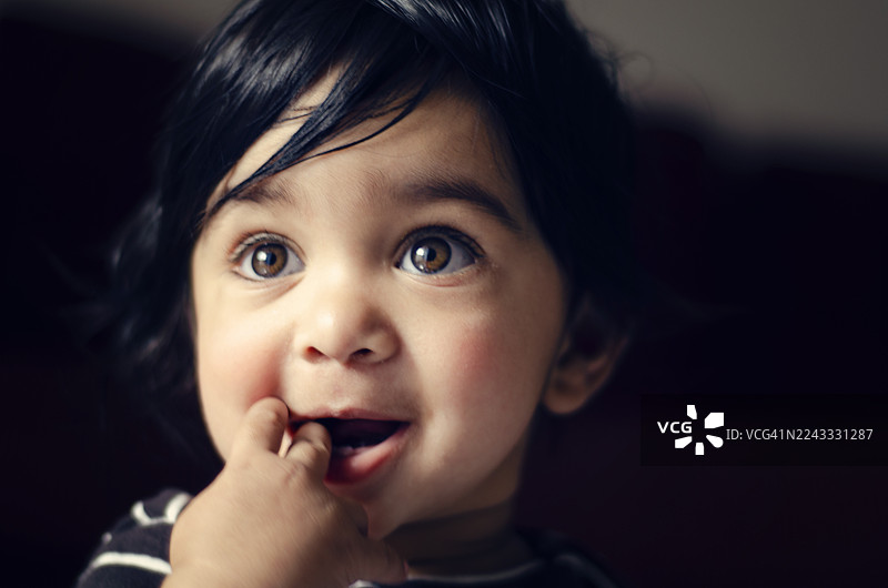 灿烂的笑容：眼神明亮、表情顽皮的可爱幼儿。一位印度男童的特写肖像。图片素材