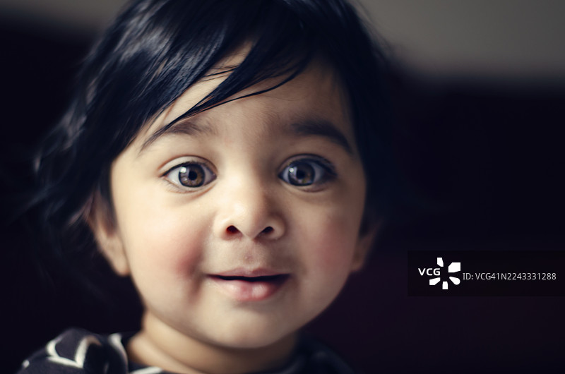 灿烂的笑容：眼神明亮、表情俏皮的可爱幼儿。一位印度男童的特写肖像。图片素材