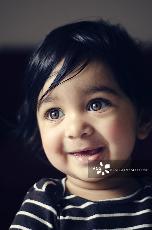 灿烂的笑容：眼神明亮、表情俏皮的可爱幼儿。印度男童的特写肖像。图片素材