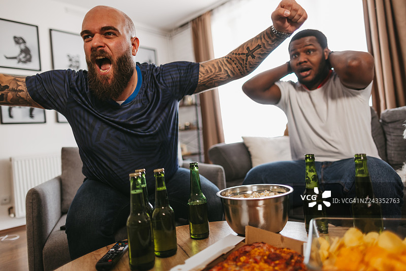 在家看比赛的快乐男性朋友，配有啤酒和零食图片素材